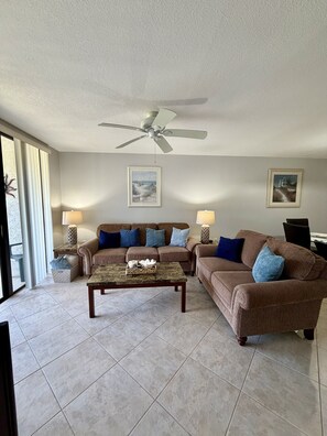 A living room with a ceiling fan, two couches, a coffee table, and two lamps.