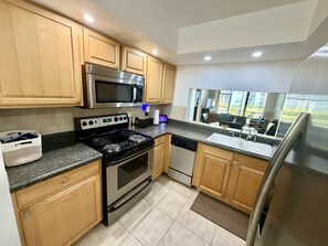 A modern kitchen with wooden cabinets, stainless steel appliances, a built-in microwave, and a dishwasher.