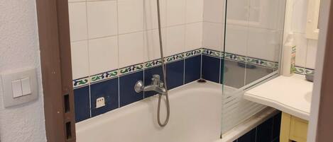 Un baño con bañera, ducha y espejo.