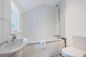 Et moderne badeværelse med badekar, vask og toilet.