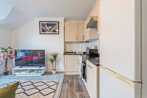Et moderne køkken med hvide skabe, en mikrobølgeovn og en indbygget ovn.