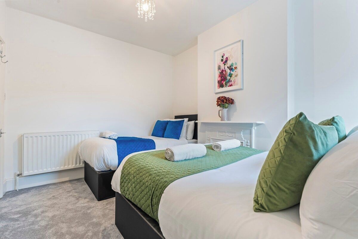 A bedroom with a bed, a nightstand, a radiator, and a wall-mounted artwork.