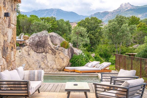 Un espace aménagé au bord de la piscine, avec des chaises longues, une petite piscine et une vue sur les montagnes.