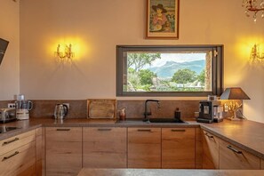 Eine Küche mit Holzausstattung, einem schwarzen Spülbecken und einem Fenster mit Blick auf Grünflächen und Berge.