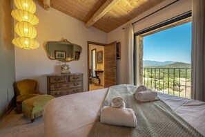 Ein Schlafzimmer mit einem Bett, einem Schminktisch, einem Spiegel und Blick auf die Landschaft.