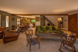 Ein geräumiger Wohnbereich mit einer Couch, Stühlen, einem Esstisch und einer Treppe.