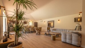 Uma sala de estar moderna com área de jantar, um sofá, uma mesa de centro e um vaso de planta.