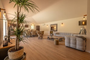 Ein modernes Wohnzimmer mit Essbereich, einer Couch, einem Couchtisch und einer Topfpflanze.