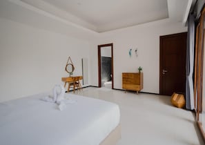 Une chambre à coucher comprenant un lit, une commode en bois, un bureau et un miroir.