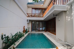 A residential property with a swimming pool, a balcony, and a two-story building.