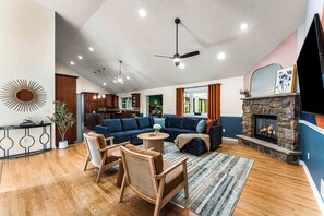 Ein geräumiges Wohnzimmer mit Kamin, Essbereich und einer Küche im Hintergrund.