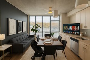 Een moderne woonruimte met een eethoek, bank, televisie en keuken.