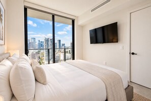 A hotel room with a large bed, a city view, and a flat-screen TV. - LUXURY 1BR/1BA DOWNTOWN APARTMENT (Miami)