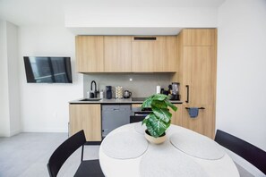 Eine moderne Küche mit Holzausstattung, einem eingebauten Geschirrspüler und einem Essbereich mit rundem Tisch und Stühlen.