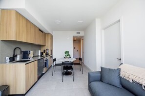 Eine moderne Küche mit Holzausstattung, einem Esstisch mit Stühlen und einem grauen Sofa.
