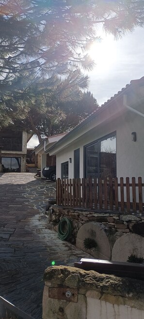 Ein Haus mit gepflasterter Auffahrt, einem Holzzaun und einem Auto im Hintergrund.