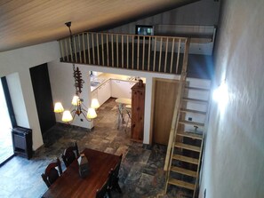 Ein Essbereich mit Holztisch und -stühlen, eine Küche mit weißen Schränken, eine Treppe und ein Chandelier.
