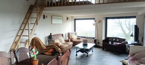 Ein Wohnzimmer mit Sofa, Couchtisch, Fernseher und einer Treppe.