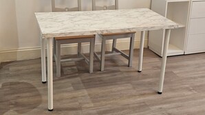 A small dining table with a marble top, two chairs, and a white cabinet in a room with wooden flooring. - Stylish Brick Lane Studio Near Tube & Dining Hub! (London)