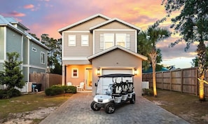 Ein zweistöckiges Haus mit Garage, Golfwagen und Holzzaun.