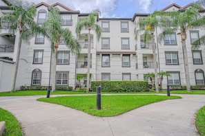 A multi-story residential building with balconies, a well-maintained lawn, and a clear sky. - Modern 3BR VistaCay Apartment Near Disney, Universal & Orlando Attractions Sleeps 7 (Orlando)