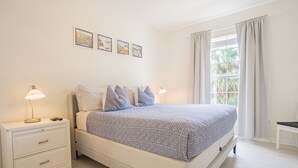 Una camera da letto con un letto, comodini, una finestra con tende e decorazioni alle pareti.