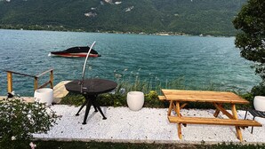 En vacker utsikt över sjön med en båt, en brygga, ett picknickbord och en sittplats.