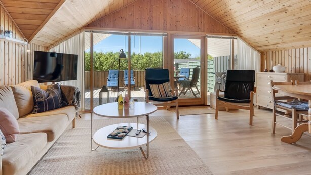 Un interior acogedor de madera con un sofá, una mesa redonda y un televisor.