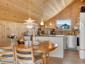 A wooden interior with a dining table, chairs, a kitchen area, and a window with a view. - "Greta" - 300m from the sea by Interhome (Thisted)