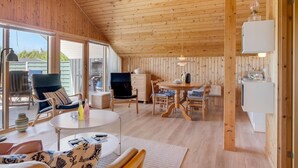 Un interior de cabaña acogedor con comedor, cocina y zona de estar con vistas.
