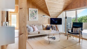 Un interior de madera acogedor con un sofá, una mesa de centro y un televisor.