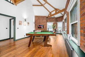 A pool table in a room with wooden flooring, brick walls, and a high ceiling with exposed beams. - Spacious 2BR • Pool Table • Workspace • City Centre (Manchester)
