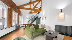 Ein Zimmer mit einem grünen Sofa, einem kleinen Tisch, einer Treppe und einer Heizung.