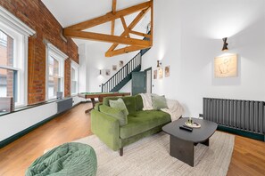 A room with a green sofa, a small table, a staircase, and a radiator. - Spacious 2BR • Pool Table • Workspace • City Centre (Manchester)