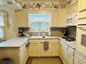 A kitchen with beige cabinets, a coffee maker, a stove, and a microwave.