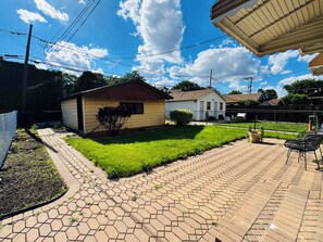 A paved patio area with a small garden, a shed, and a fenced yard.