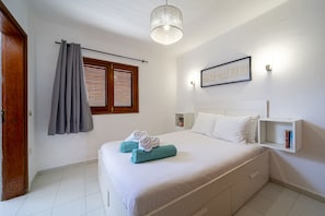 Ein Hotelzimmer mit einem Bett, einem Fenster mit Jalousien, einem Wandregal und einer Deckenleuchte.