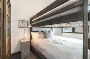 A bunk bed with a wooden headboard, a bedside table with drawers, a wall-mounted lamp, and a framed inspirational quote. - Modern Whitefish Loft | Sleeps 6 | Downtown Whitefish, Mountain Adventure Awaits (Whitefish)