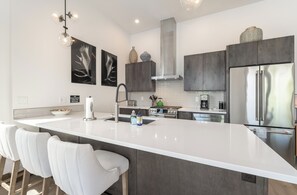 A modern kitchen with a large island, stainless steel appliances, and minimalist decor. - Modern Whitefish Loft | Sleeps 6 | Downtown Whitefish, Mountain Adventure Awaits (Whitefish)