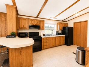 A kitchen with wooden cabinets, a stove, a refrigerator, and a coffee bar.