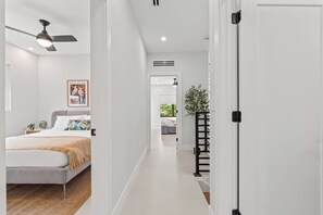 Ein modernes Hotelzimmer mit einem Bett, einem Deckenventilator, einem Nachttisch und einem gerahmten Bild an der Wand.