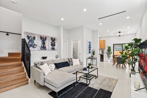 Ein stilvolles Wohnzimmer mit einer Couch, einem Couchtisch und Kunstwerken an den Wänden.