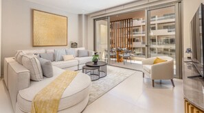 Ein modernes Wohnzimmer mit Sofa, Couchtisch und Fernseher.