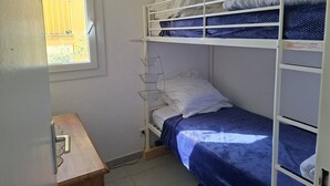 Ein Schlafraum mit Etagenbetten, einem Fenster, einem Schreibtisch und einer Pendelleuchte.