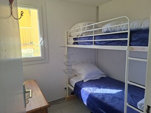 Ein Schlafraum mit Etagenbetten, einem Fenster, einem Schreibtisch und einer Pendelleuchte.
