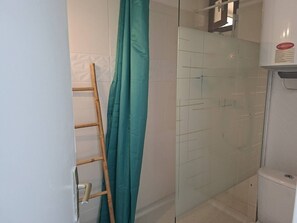 Ein Badezimmer mit Duschkabine aus Glas, einer Holzleiter und einer Toilette.
