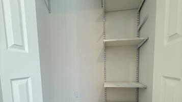 A closet with white shelving units and a wooden floor.