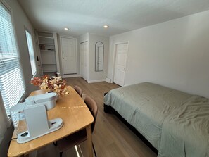 Una camera da letto con un letto, una scrivania con un computer, una sedia e una finestra con persiane.