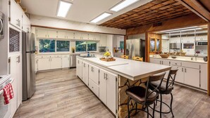 A modern kitchen with white cabinets, a large island, and a wooden ceiling. - Camp Nelson Chalet + Bunkhouse | Hot Tub | Game Room (Springville)