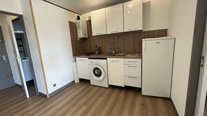 Eine kleine Küche mit Waschmaschine, Kühlschrank und Holzboden.